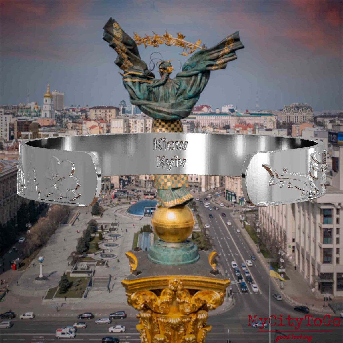 Innenseite eines silbernen Armreifs mit Reliefs bekannter Sehenswürdigkeiten der Stadt Kiew und einer Gravur des Stadtnamens. Den Hintergrund bildet eine Ansicht der Stadt Kiew.