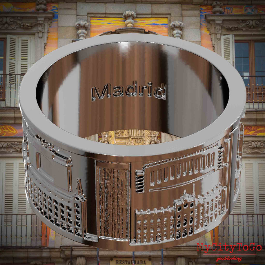 Versilberter Ring mit Reliefs bekannter Sehenswürdigkeiten der Stadt Madrid und einer Gravur des Stadtnamens auf der Innenseite. Den Hintergrund bildet eine Ansicht der Stadt Madrid.