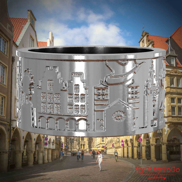 Silberner Ring mit Reliefs bekannter Sehenswürdigkeiten der Stadt Muenster. Den Hintergrund bildet eine Ansicht der Stadt Muenster.