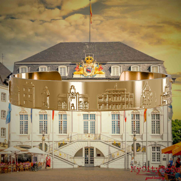 Vergoldeter Armreif mit Reliefs bekannter Sehenswürdigkeiten der Stadt Bonn. Den Hintergrund bildet eine Ansicht der Stadt Bonn.