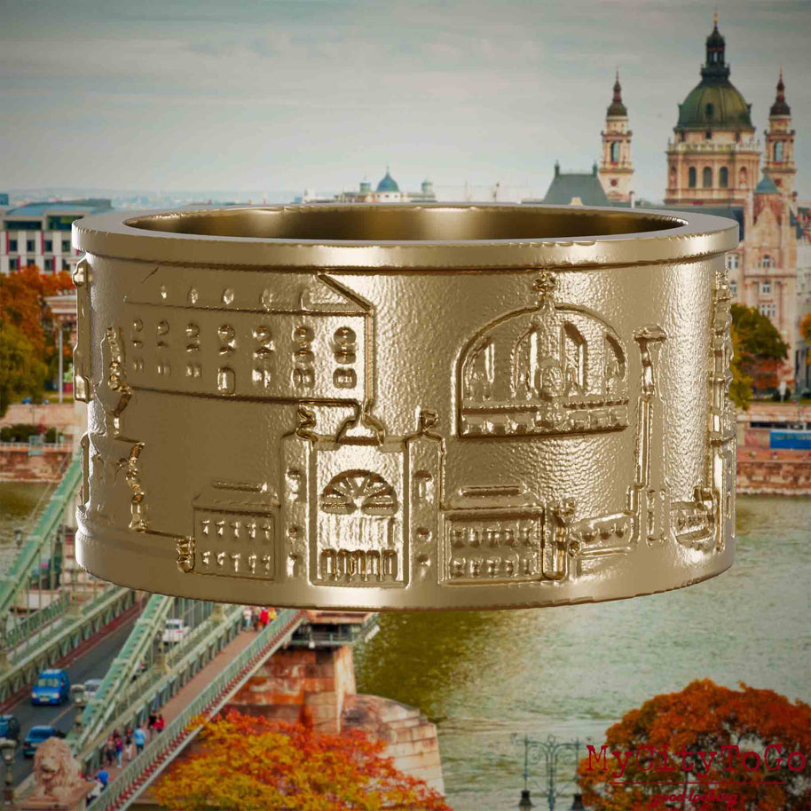 Ring aus vergoldetem Edelstahl mit Reliefs bekannter Sehenswürdigkeiten der Stadt Budapest. Den Hintergrund bildet eine Ansicht der Stadt Budapest.
