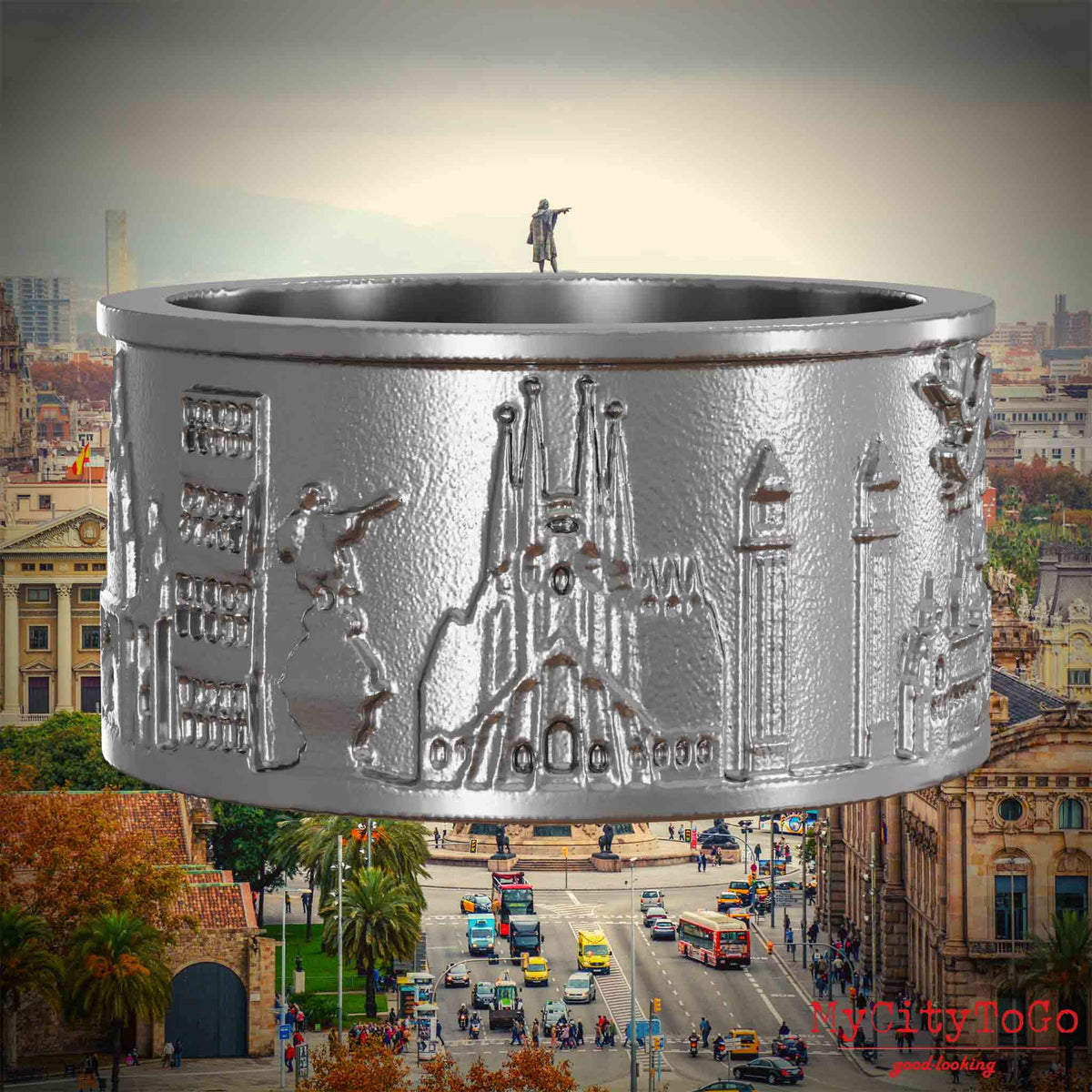 Ring aus Edelstahl mit Reliefs bekannter Sehenswürdigkeiten der Stadt Barcelona. Den Hintergrund bildet eine Ansicht der Stadt Barcelona.