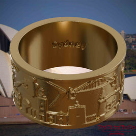 Ring aus vergoldetem Edelstahl mit Reliefs bekannter Sehenswürdigkeiten der Stadt Sydney und einer Gravur des Stadtnamens auf der Innenseite. Den Hintergrund bildet eine Ansicht der Stadt Sydney.
