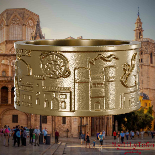 Ring aus vergoldetem Edelstahl mit Reliefs bekannter Sehenswürdigkeiten der Stadt Valencia. Den Hintergrund bildet eine Ansicht der Stadt Valencia.