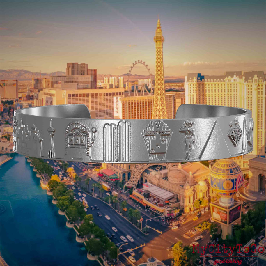 Armreif aus Edelstahl mit Reliefs bekannter Sehenswürdigkeiten der Stadt Las Vegas. Den Hintergrund bildet eine Ansicht der Stadt Las Vegas.