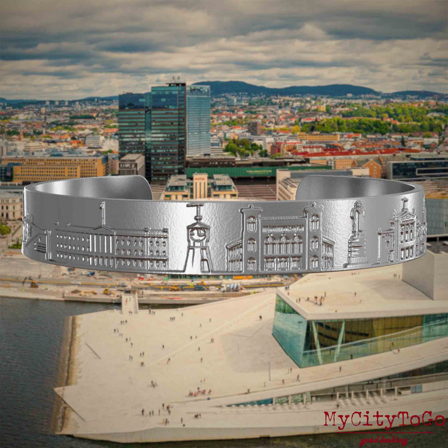 Armreif aus Edelstahl mit Reliefs bekannter Sehenswürdigkeiten der Stadt Oslo. Den Hintergrund bildet eine Ansicht der Stadt Oslo.