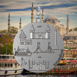 Halskette mit Drehwirbel und Vorderseite eines Schmuckanhängers aus Edelstahl, auf dem Reliefs bekannter Sehenswürdigkeiten der Stadt Istanbul abgebildet sind. Den Hintergrund bildet eine Ansicht der Stadt Istanbul.
