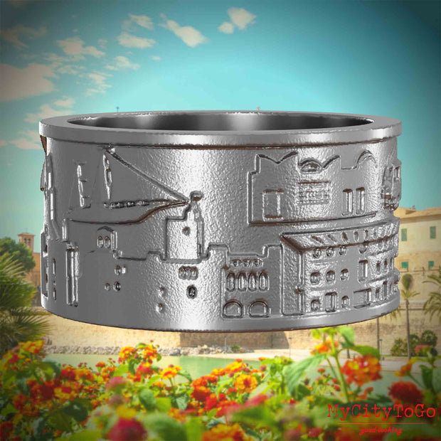Ring aus Edelstahl mit Reliefs bekannter Sehenswürdigkeiten der Stadt Palma de Mallorca. Den Hintergrund bildet eine Ansicht der Stadt Palma de Mallorca.