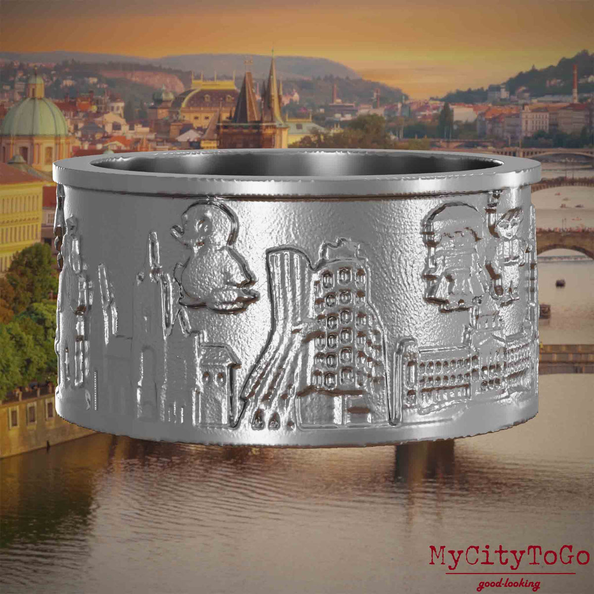Ring aus Edelstahl mit Reliefs bekannter Sehenswürdigkeiten der Stadt Prag. Den Hintergrund bildet eine Ansicht der Stadt Prag.