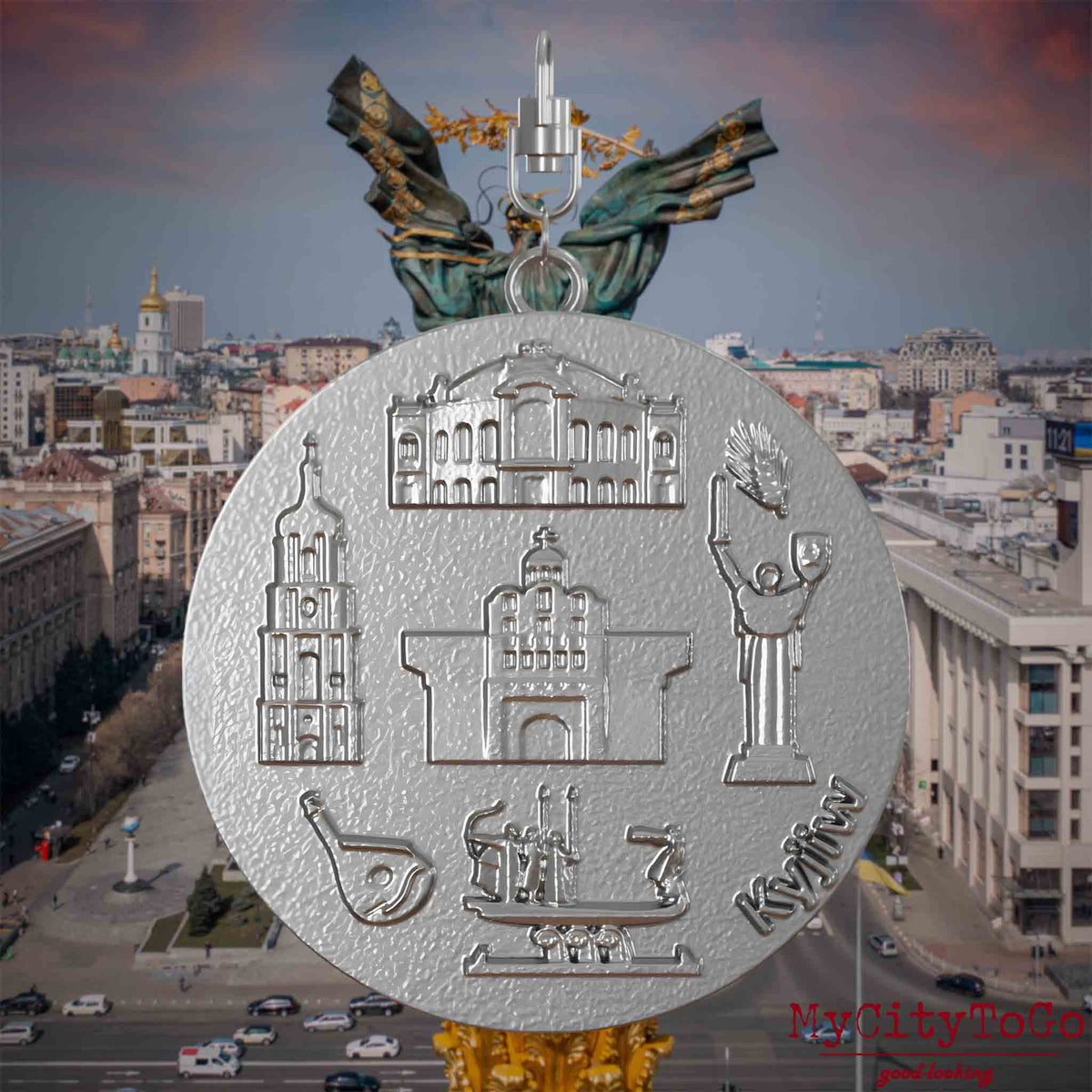 Halskette mit Drehwirbel und Vorderseite eines Schmuckanhängers aus Edelstahl, auf dem Reliefs bekannter Sehenswürdigkeiten der Stadt Kyjiw abgebildet sind. Den Hintergrund bildet eine Ansicht der Stadt Kyjiw.
