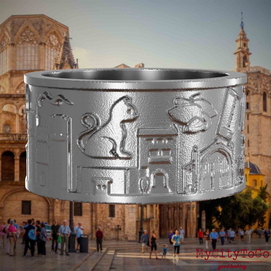 Ring aus Edelstahl mit Reliefs bekannter Sehenswürdigkeiten der Stadt Valencia. Den Hintergrund bildet eine Ansicht der Stadt Valencia.