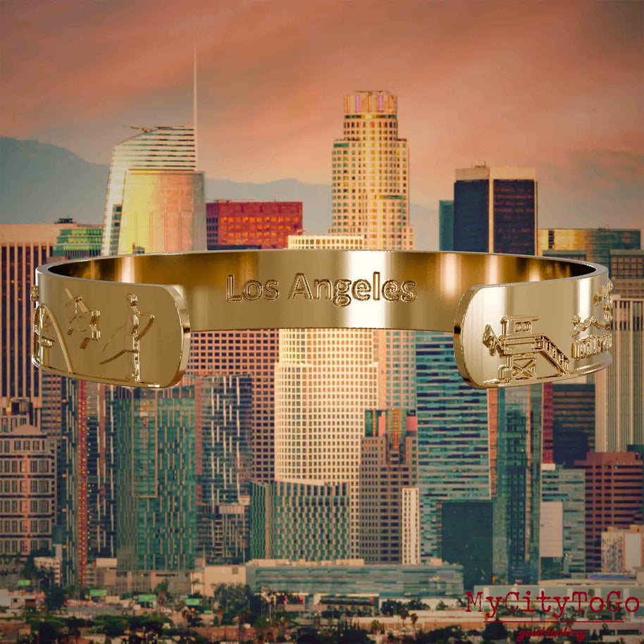Innenseite eines vergoldeten Armreifs mit Reliefs bekannter Sehenswürdigkeiten der Stadt Los Angeles und einer Gravur des Stadtnamens. Den Hintergrund bildet eine Ansicht der Stadt Los Angeles.