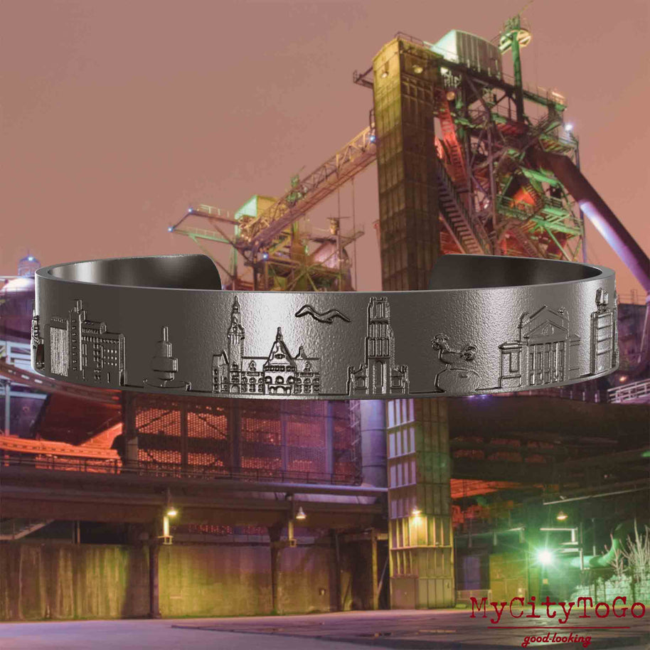 Bangle made of titanium with reliefs of well-known landmarks of the city of Duisburg. The background features a view of the city of Duisburg.