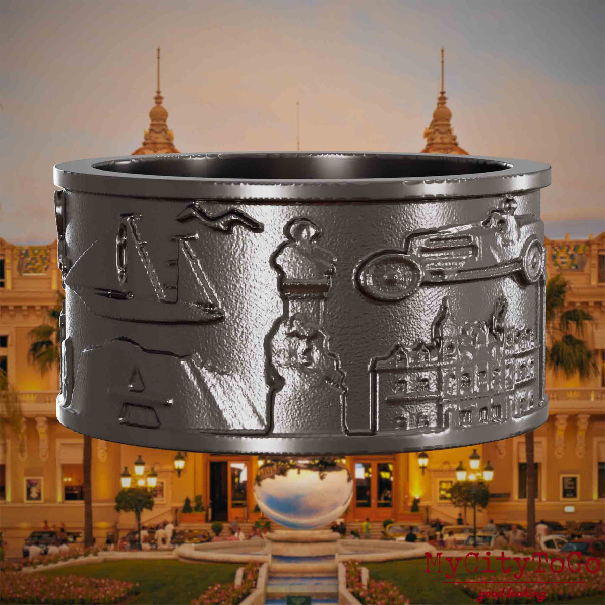 Ring aus Titan mit Reliefs bekannter Sehenswürdigkeiten der Stadt Monte Carlo. Den Hintergrund bildet eine Ansicht der Stadt Monte Carlo.