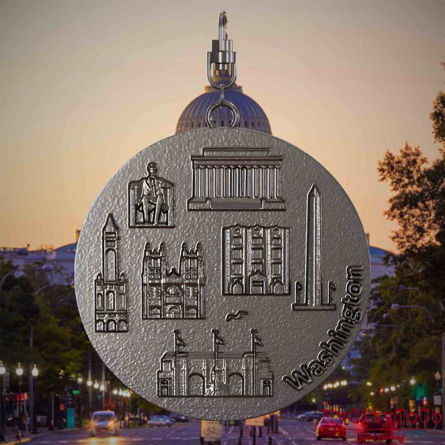 Halskette mit Drehwirbel und Vorderseite eines Schmuckanhängers aus Titan, auf dem Reliefs bekannter Sehenswürdigkeiten der Stadt Washington abgebildet sind. Den Hintergrund bildet eine Ansicht der Stadt Washington.
