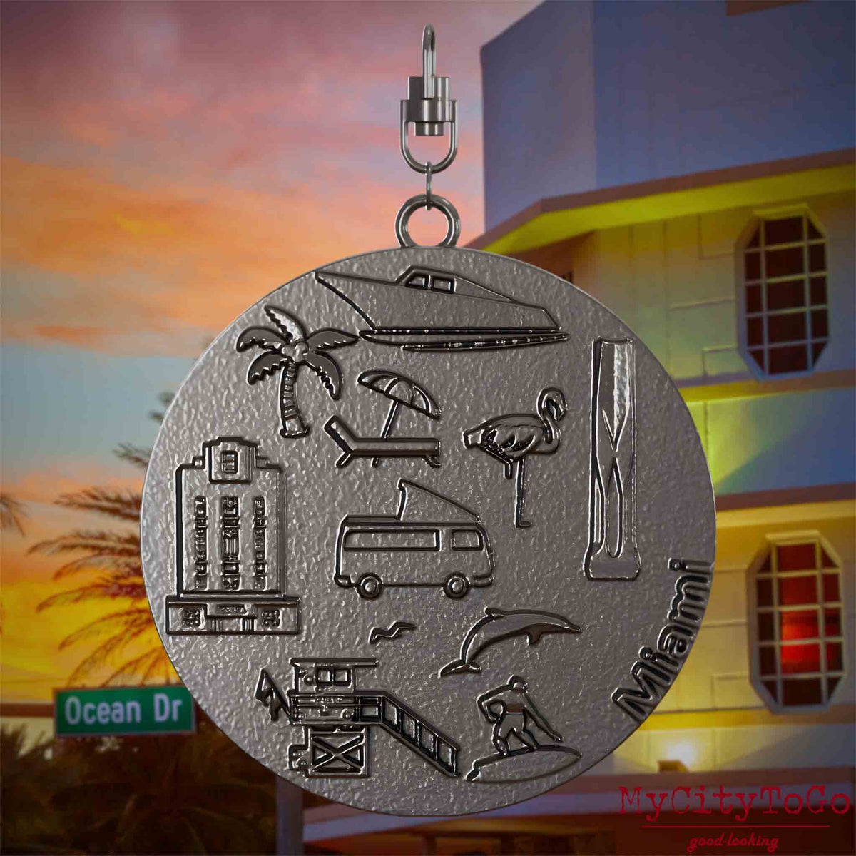 Halskette mit Drehwirbel und Rückseite eines Schmuckanhängers aus Titan, auf dem Reliefs bekannter Sehenswürdigkeiten der Stadt Miami abgebildet sind. Den Hintergrund bildet eine Ansicht der Stadt Miami.
