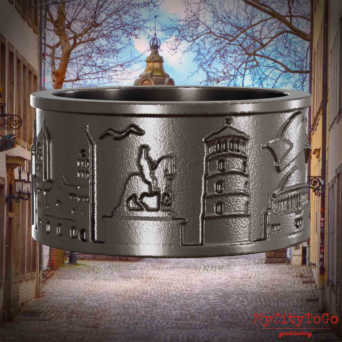 Ring aus Titan mit Reliefs bekannter Sehenswürdigkeiten der Stadt Duesseldorf. Den Hintergrund bildet eine Ansicht der Stadt Duesseldorf.