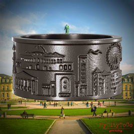 Ring aus Titan mit Reliefs bekannter Sehenswürdigkeiten der Stadt Stuttgart. Den Hintergrund bildet eine Ansicht der Stadt Stuttgart.