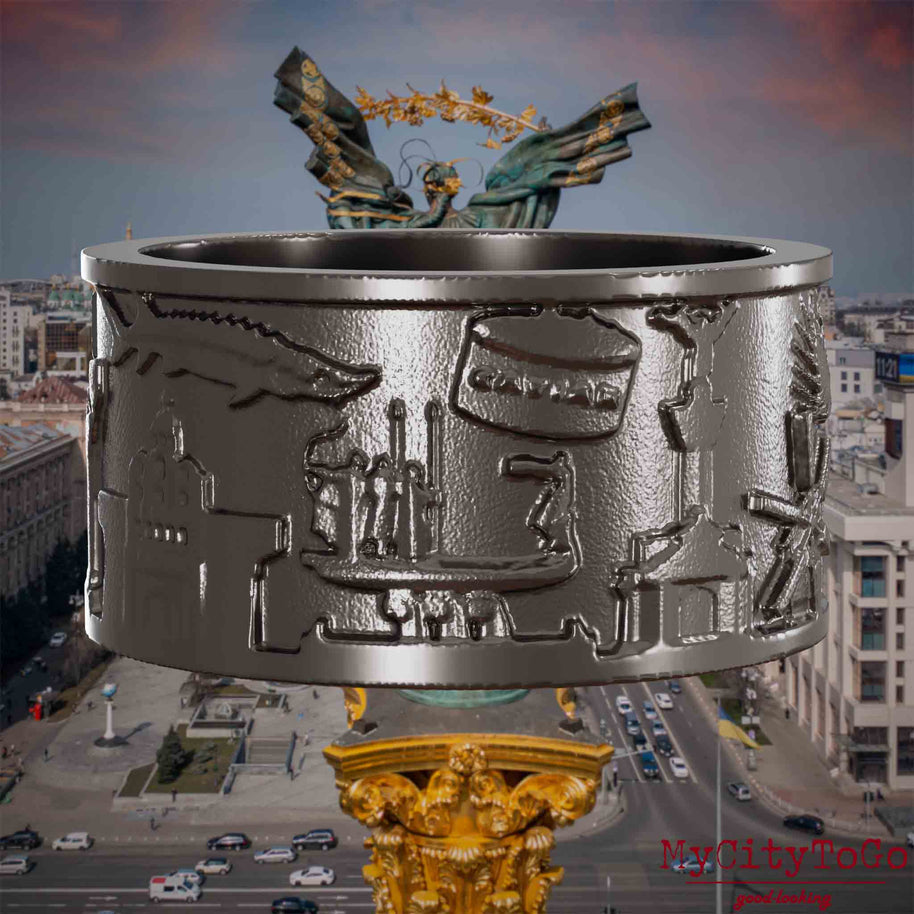 Ring aus Titan mit Reliefs bekannter Sehenswürdigkeiten der Stadt Kiew. Den Hintergrund bildet eine Ansicht der Stadt Kiew.