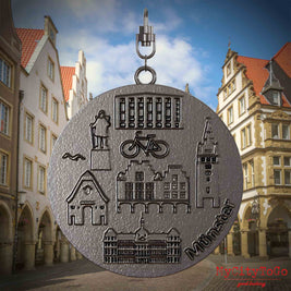 Halskette mit Drehwirbel und Rückseite eines Schmuckanhängers aus Titan, auf dem Reliefs bekannter Sehenswürdigkeiten der Stadt Muenster abgebildet sind. Den Hintergrund bildet eine Ansicht der Stadt Muenster.