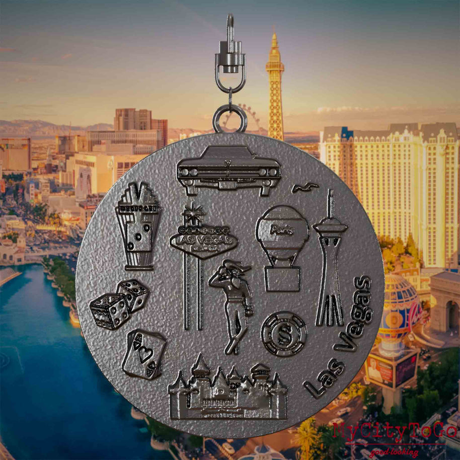 Necklace with a swivel clasp and the back of a titanium jewelry pendant featuring reliefs of famous Las Vegas landmarks. The background shows a view of the city of Las Vegas.