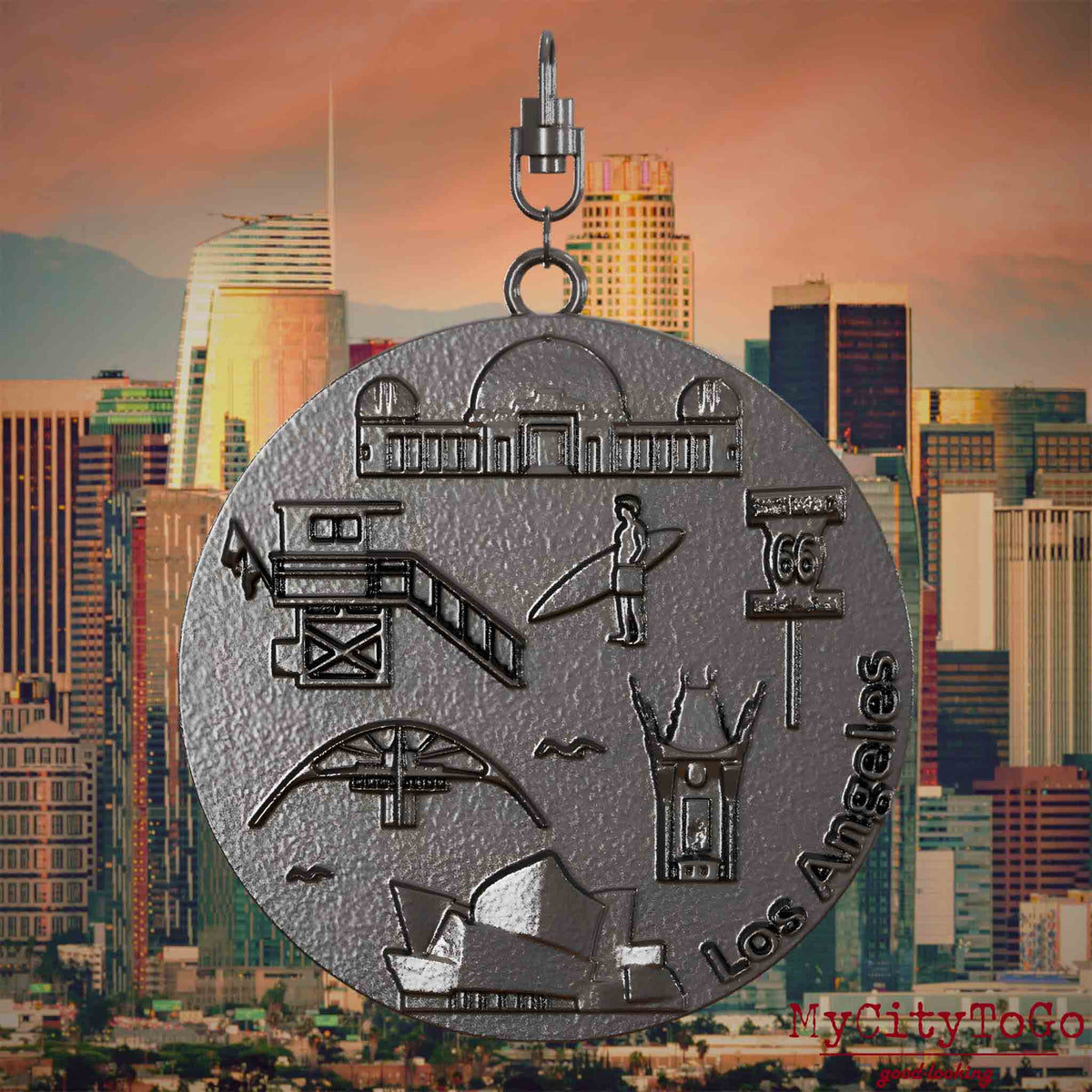 Halskette mit Drehwirbel und Rückseite eines Schmuckanhängers aus Titan, auf dem Reliefs bekannter Sehenswürdigkeiten der Stadt Los Angeles abgebildet sind. Den Hintergrund bildet eine Ansicht der Stadt Los Angeles.
