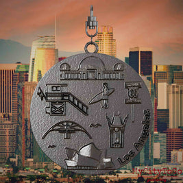 Halskette mit Drehwirbel und Rückseite eines Schmuckanhängers aus Titan, auf dem Reliefs bekannter Sehenswürdigkeiten der Stadt Los Angeles abgebildet sind. Den Hintergrund bildet eine Ansicht der Stadt Los Angeles.
