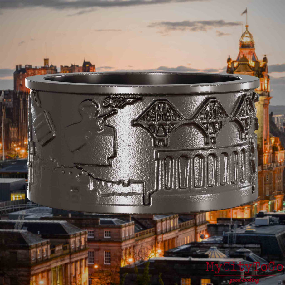 Ring aus Titan mit Reliefs bekannter Sehenswürdigkeiten der Stadt Edinburgh. Den Hintergrund bildet eine Ansicht der Stadt Edinburgh.