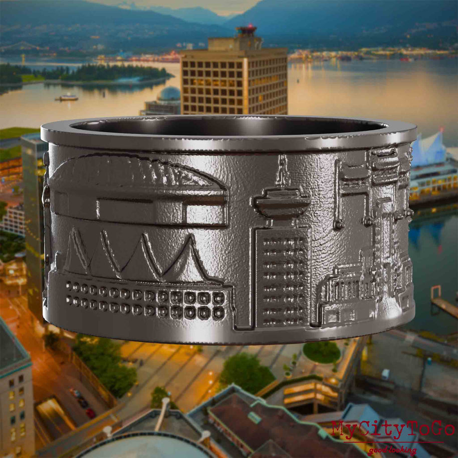 Ring aus Titan mit Reliefs bekannter Sehenswürdigkeiten der Stadt Vancouver. Den Hintergrund bildet eine Ansicht der Stadt Vancouver.