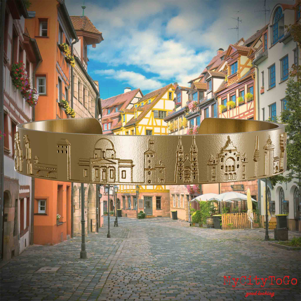 Armreif aus vergoldetem Edelstahl mit Reliefs bekannter Sehenswürdigkeiten der Stadt Nürnberg. Den Hintergrund bildet eine Ansicht der Stadt  Nuernberg.