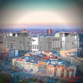 Versilberter Armreif mit Reliefs bekannter Sehenswürdigkeiten der Stadt Essen. Den Hintergrund bildet eine Ansicht der Stadt Essen.