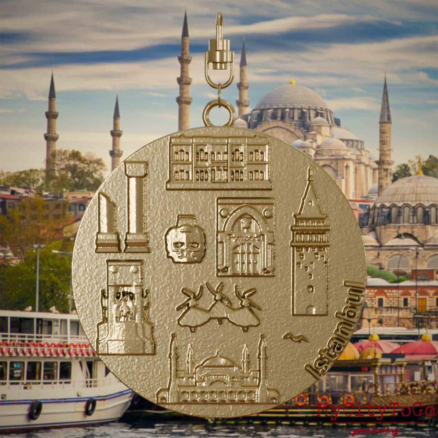 Halskette mit Drehwirbel und Rückseite eines Schmuckanhängers aus vergoldetem Edelstahl, auf dem Reliefs bekannter Sehenswürdigkeiten der Stadt Istanbul abgebildet sind. Den Hintergrund bildet eine Ansicht der Stadt Istanbul.
