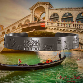 Armreif aus Titan mit Reliefs bekannter Sehenswürdigkeiten der Stadt Venedig. Den Hintergrund bildet eine Ansicht der Stadt Venedig.