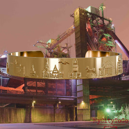 Gold-plated Bangle with reliefs of well-known landmarks of the city of Duisburg. The background features a view of the city of Duisburg.