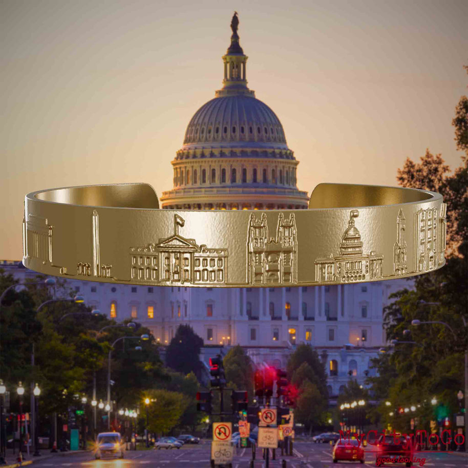 Armreif aus vergoldetem Edelstahl mit Reliefs bekannter Sehenswürdigkeiten der Stadt Washington. Den Hintergrund bildet eine Ansicht der Stadt Washington.