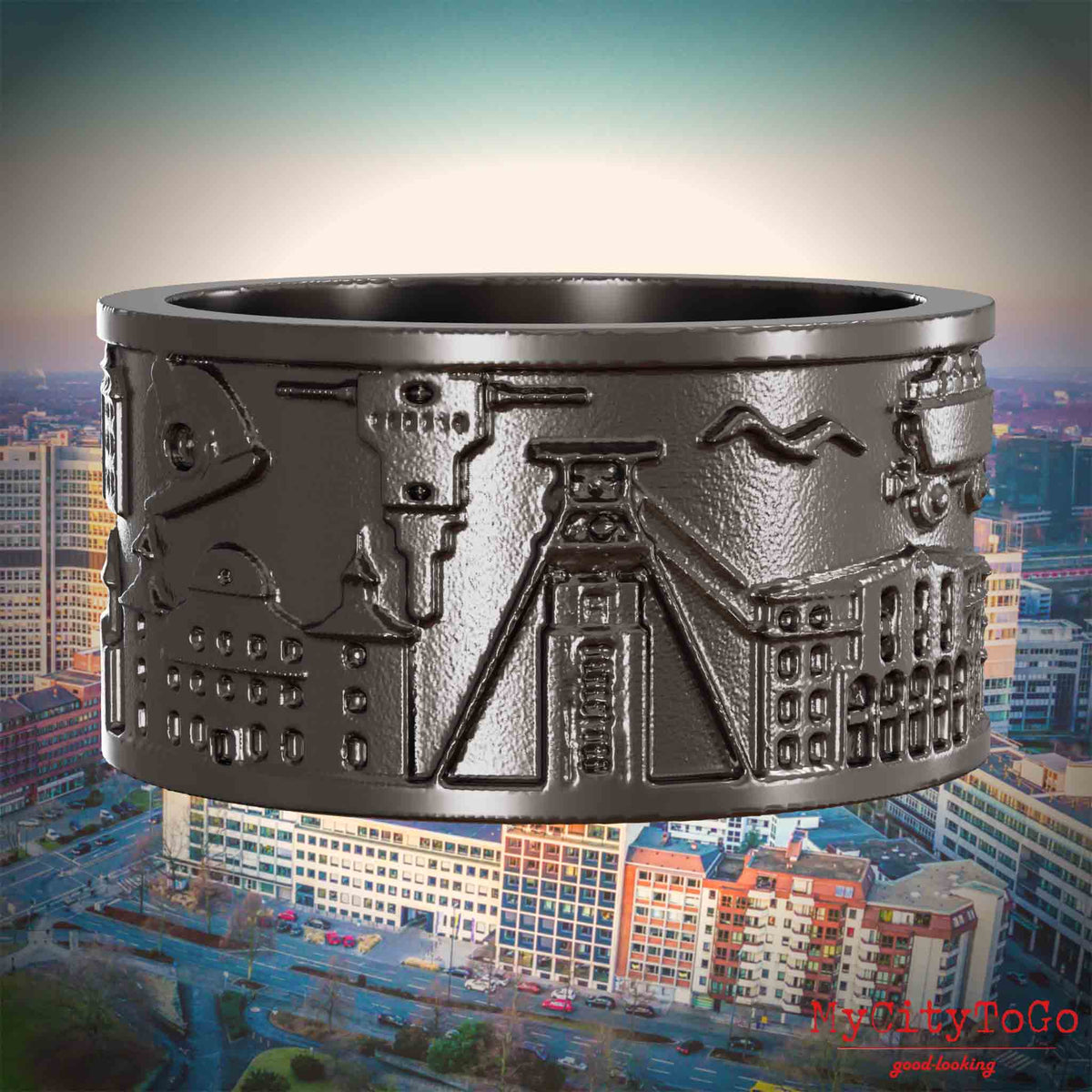 Ring aus Titan mit Reliefs bekannter Sehenswürdigkeiten der Stadt Essen. Den Hintergrund bildet eine Ansicht der Stadt Essen.