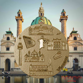 Halskette mit Drehwirbel und Rückseite eines Schmuckanhängers aus vergoldetem Edelstahl, auf dem Reliefs bekannter Sehenswürdigkeiten der Stadt Wien abgebildet sind. Den Hintergrund bildet eine Ansicht der Stadt Wien.
