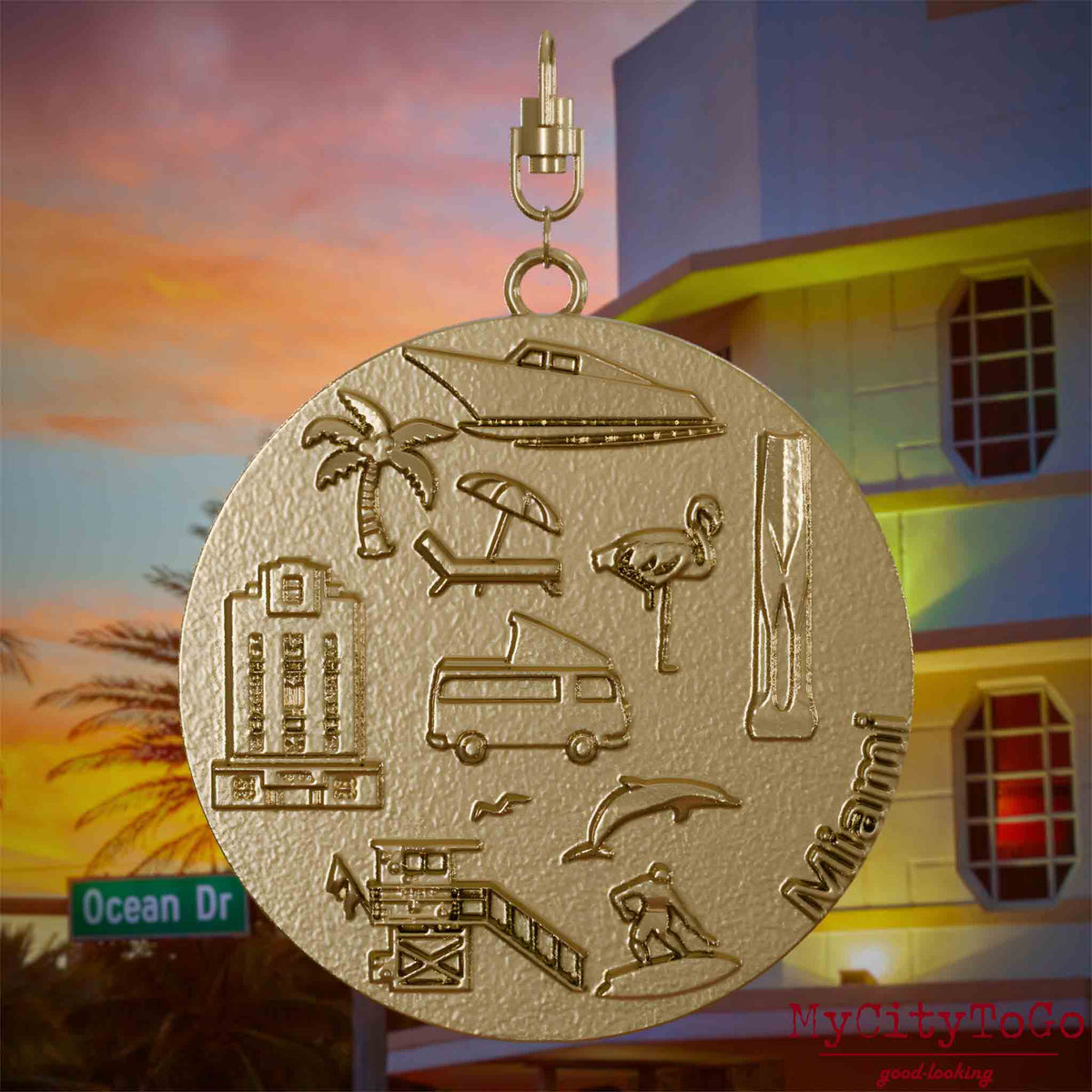 Halskette mit Drehwirbel und Rückseite eines Schmuckanhängers aus vergoldetem Edelstahl, auf dem Reliefs bekannter Sehenswürdigkeiten der Stadt Miami abgebildet sind. Den Hintergrund bildet eine Ansicht der Stadt Miami.
