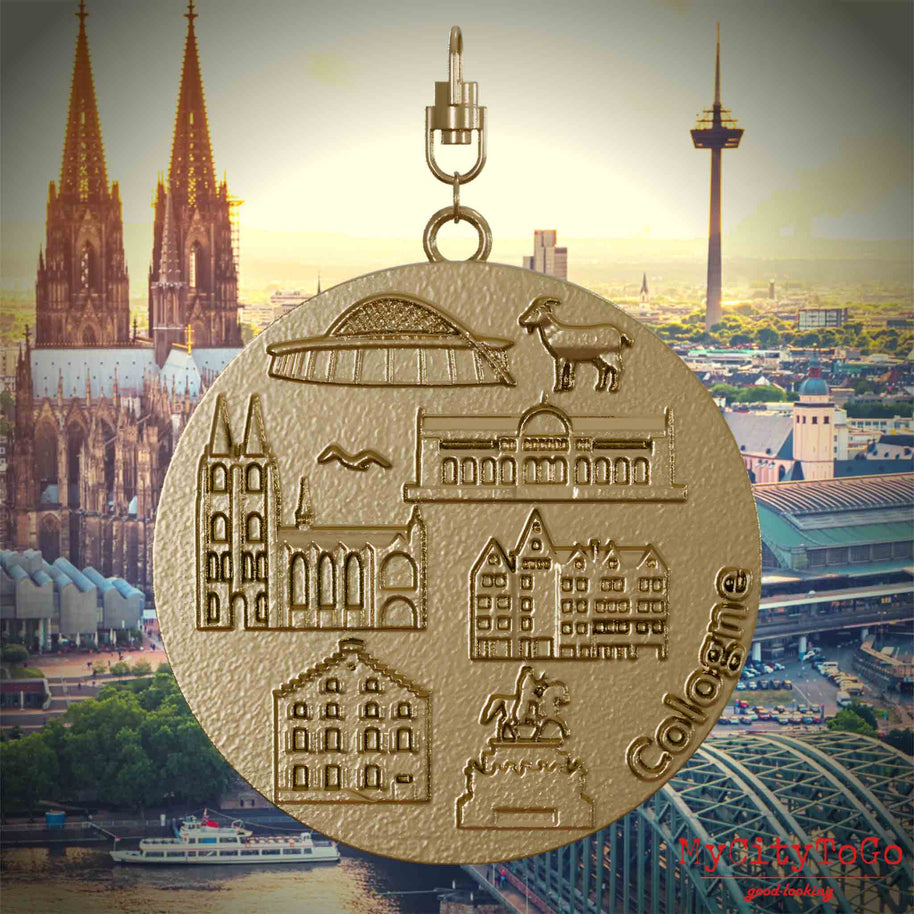 Halskette mit Drehwirbel und Vorderseite eines Schmuckanhängers aus vergoldetem Edelstahl, auf dem Reliefs bekannter Sehenswürdigkeiten der Stadt Koeln abgebildet sind. Den Hintergrund bildet eine Ansicht der Stadt Koeln.
