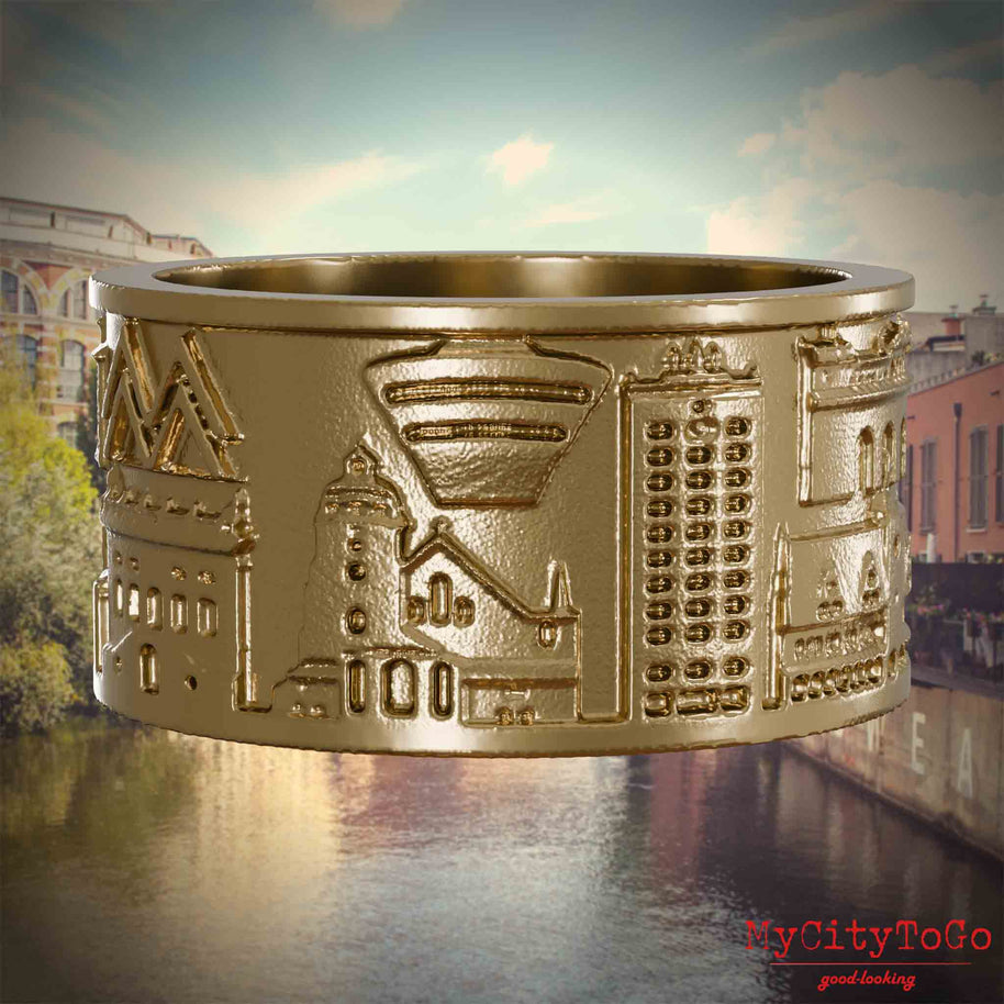 Ring aus vergoldetem Edelstahl mit Reliefs bekannter Sehenswürdigkeiten der Stadt Leipzig. Den Hintergrund bildet eine Ansicht der Stadt Leipzig.