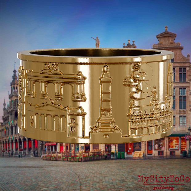 Vergoldeter Ring mit Reliefs bekannter Sehenswürdigkeiten der Stadt Bruessel. Den Hintergrund bildet eine Ansicht der Stadt Bruessel.