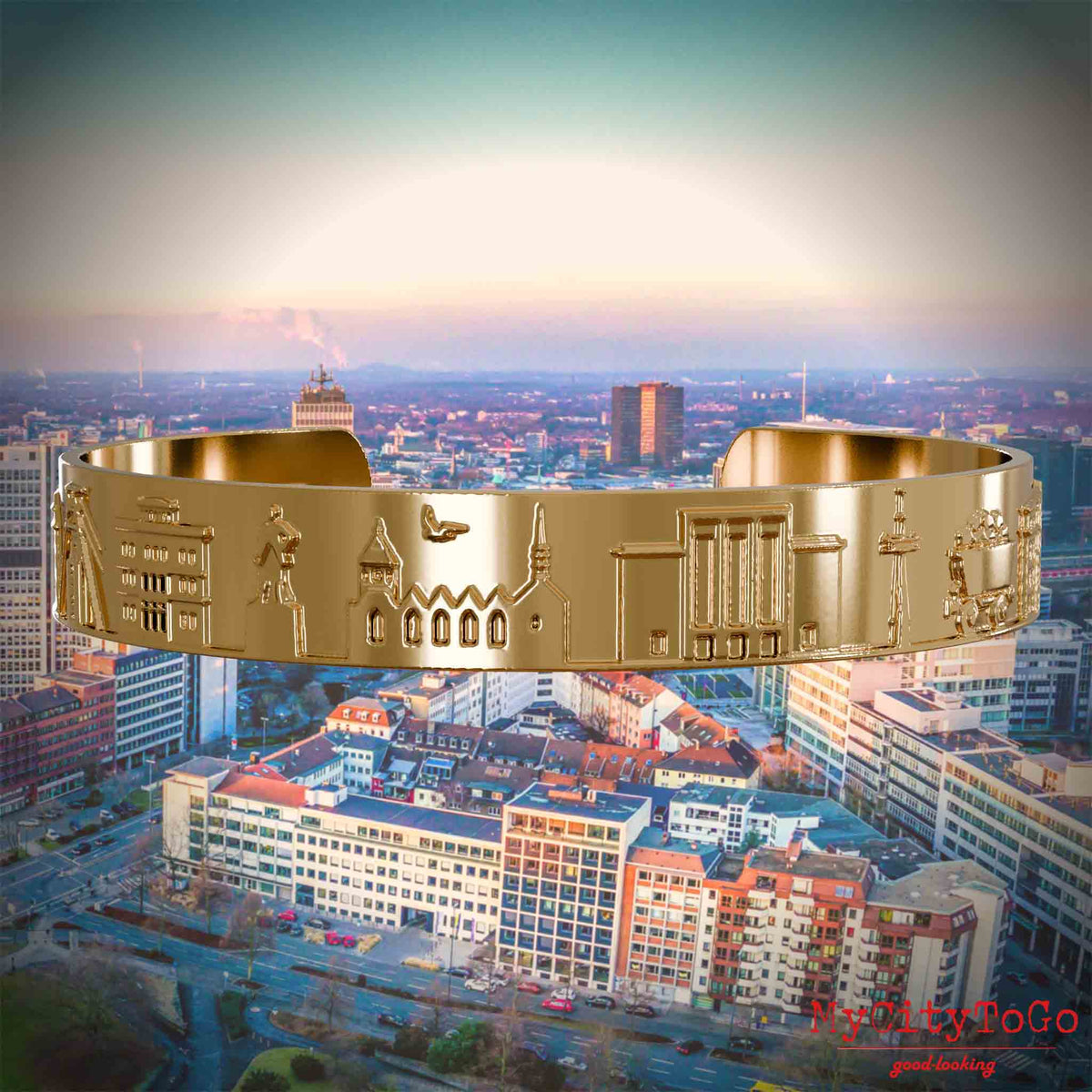 Vergoldeter Armreif mit Reliefs bekannter Sehenswürdigkeiten der Stadt Essen. Den Hintergrund bildet eine Ansicht der Stadt Essen.