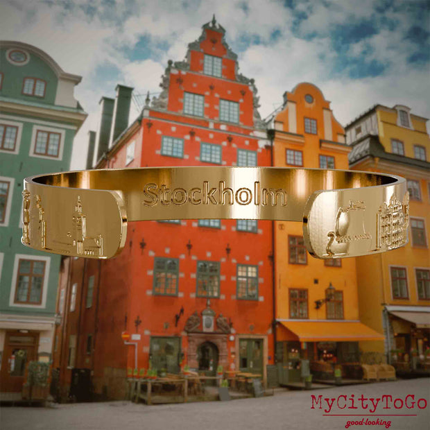 Innenseite eines vergoldeten Armreifs mit Reliefs bekannter Sehenswürdigkeiten der Stadt Stockholm und einer Gravur des Stadtnamens. Den Hintergrund bildet eine Ansicht der Stadt Stockholm.