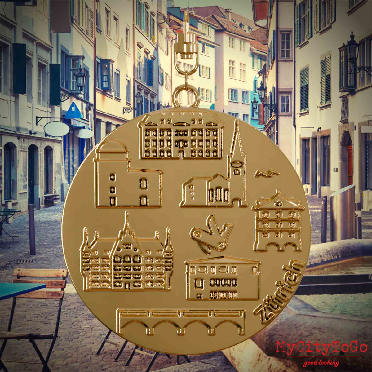 Halskette mit Drehwirbel und Rückseite eines vergoldeten Schmuckanhängers, auf dem Reliefs bekannter Sehenswürdigkeiten der Stadt Zuerich abgebildet sind. Den Hintergrund bildet eine Ansicht der Stadt Zuerich.
