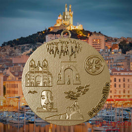 Halskette mit Drehwirbel und Rückseite eines Schmuckanhängers aus vergoldetem Edelstahl, auf dem Reliefs bekannter Sehenswürdigkeiten der Stadt Marseille abgebildet sind. Den Hintergrund bildet eine Ansicht der Stadt Marseille.
