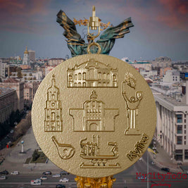 Halskette mit Drehwirbel und Vorderseite eines Schmuckanhängers aus vergoldetem Edelstahl, auf dem Reliefs bekannter Sehenswürdigkeiten der Stadt Kyjiw abgebildet sind. Den Hintergrund bildet eine Ansicht der Stadt Kyjiw.
