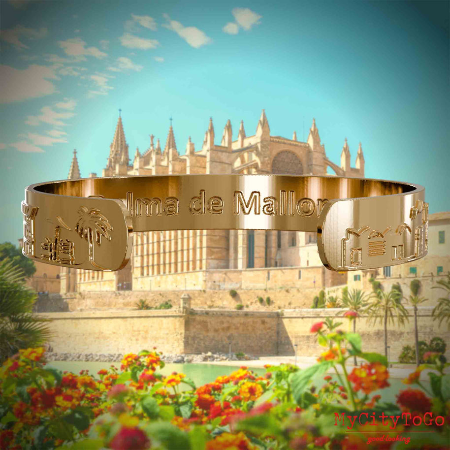 Innenseite eines vergoldeten Armreifs mit Reliefs bekannter Sehenswürdigkeiten der Stadt Palma de Mallorca und einer Gravur des Stadtnamens . Den Hintergrund bildet eine Ansicht der Stadt Palma de Mallorca.