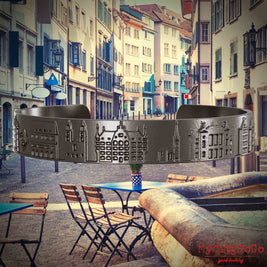 Armreif aus Titan mit Reliefs bekannter Sehenswürdigkeiten der Stadt Zuerich. Den Hintergrund bildet eine Ansicht der Stadt Zuerich.